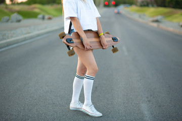 Beautiful sexy young girl in short shorts walking with longboard in sunny weather. Leisure. Healthy lifestyle. Extreme sports. Fashion look, outdoor hipster portrait, Bali, sneakers,hipster,sunse