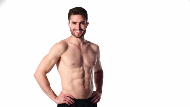 A young sports man with a beard, looking in frame and smiling. The naked torso and muscular muscles of men. Handsome guy looking at camera on a white background