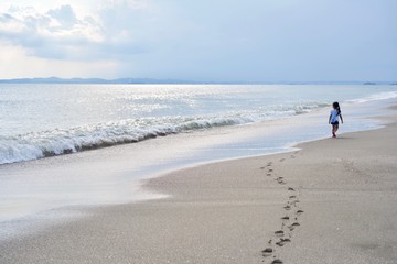 海辺を足跡つけて遠くまで歩く子供