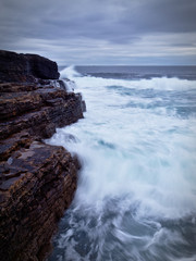Waves crashing on the rocky cliffs of the Irish west coast at dusk (long exposure)
