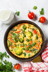 Frittata with vegetables on white stone table.