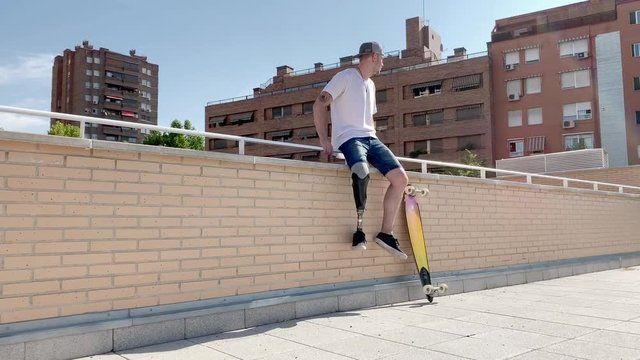 Young man with orthopedic leg prosthesis jumping between buildings practicing parkour