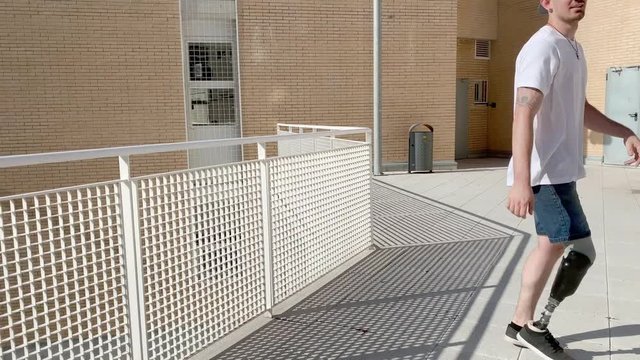 Young man with orthopedic leg prosthesis jumping between buildings practicing parkour