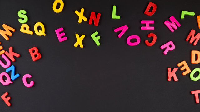 multicolored plastic letters of the English alphabet on a black chalk board
