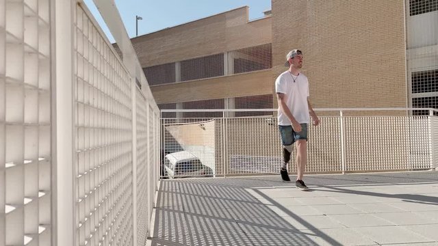 Young man with orthopedic leg prosthesis jumping between buildings practicing parkour