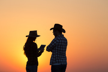 Fototapeta premium Farmers man and woman standing in field at sunset