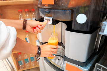 Girl squeezes juice in a juicer in the supermarket