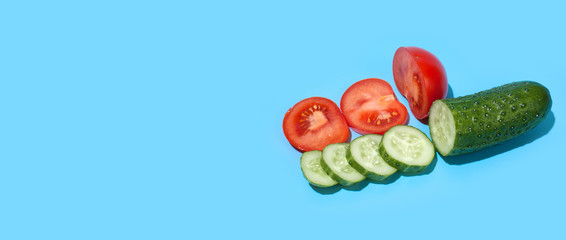 Ripe green cucumber and red tomato on blue background. Healthy eating and dieting concept.
