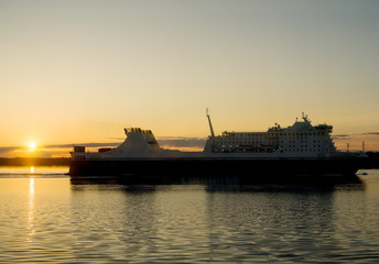 Obraz premium Passenger and freight ferry against a sunset in the Baltic sea.