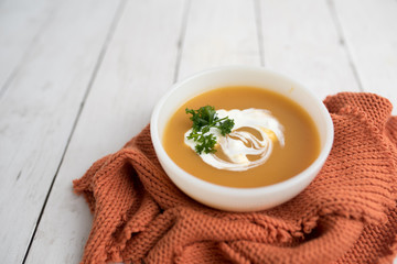 Pumpkin soup with sour cream in white small bowl 