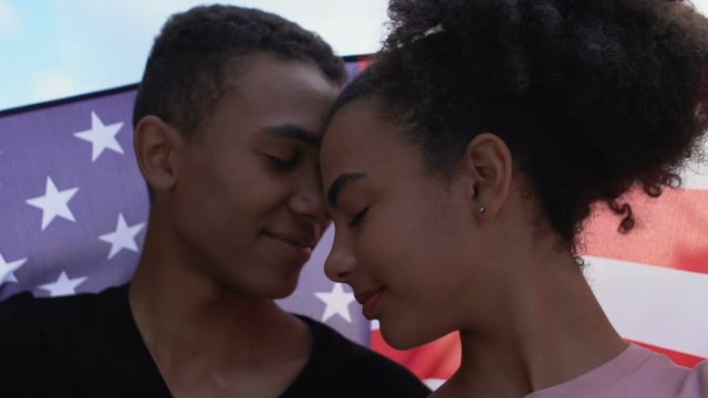Afro-american teen couple in love covered USA flag touching foreheads patriotism