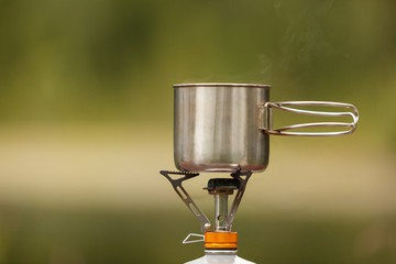 The camping iron mug with a gas burner on background