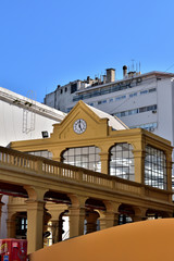 Terraced construction with large windows, triangular dome with decorative clock on the facade. The base of support are high columns in intense yellow, small wall of lower circular line.