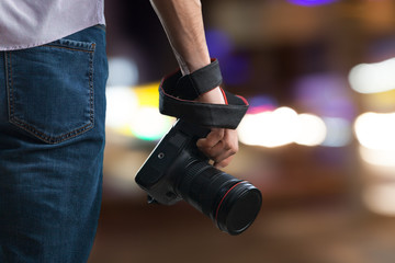 Young man holds black modern digital camera