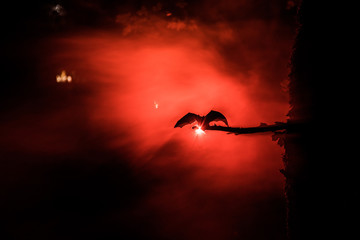 Horror Halloween concept. The bat is spreading its wings sitting on the tree at misty night.