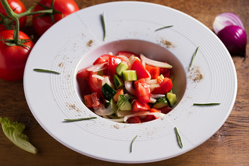 Healthy vegetable salad of fresh tomatoes, cucumbers, bell pepper, onions and herbs. Diet menu
