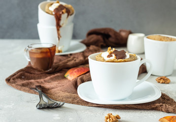 Carrot op pumpkin mug cupcake with whipped cream, caramel sauce and walnuts in a white ceramic mug. Cozy autumn or winter breakfast. Healthy dessert. 