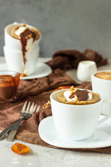 Carrot op pumpkin mug cupcake with whipped cream, caramel sauce and walnuts in a white ceramic mug. Cozy autumn or winter breakfast. Healthy dessert. 