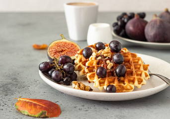 Traditional Belgian waffles with caramel sauce, grapes and figs. Cozy autumn or winter breakfast. Comfort food.