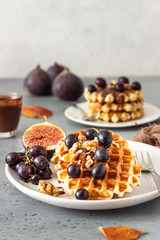 Traditional Belgian waffles with caramel sauce, grapes and figs. Cozy autumn or winter breakfast. Comfort food.