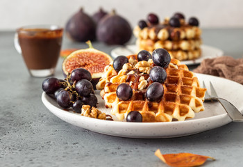 Traditional Belgian waffles with caramel sauce, grapes and figs. Cozy autumn or winter breakfast. Comfort food.