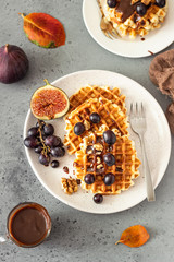 Traditional Belgian waffles with caramel sauce, grapes and figs. Cozy autumn or winter breakfast. Comfort food.