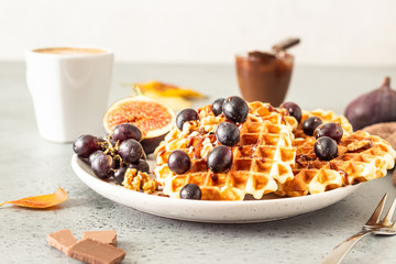 Traditional Belgian waffles with caramel sauce, grapes and figs. Cozy autumn or winter breakfast. Comfort food.