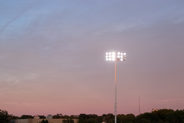 Lights over an American football field during evening sunset