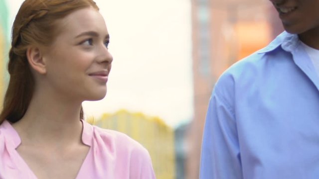 Happy multiracial young couple smiling and walking on city street, romantic date
