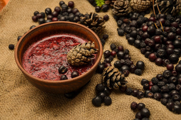 Jam of black Rowan, cones and branches of the Christmas tree on the background of burlap. Preparations for the winter. Gift of nature.