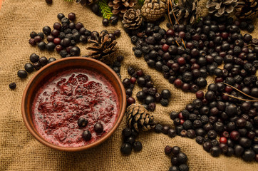 Jam of black Rowan, cones and branches of the Christmas tree on the background of burlap. Preparations for the winter. Gift of nature.