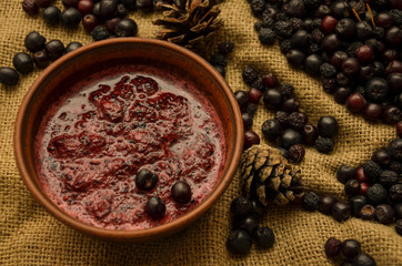 Jam of black Rowan, cones and branches of the Christmas tree on the background of burlap. Preparations for the winter. Gift of nature.