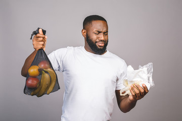 Zero waste concept. African american black men is holding mesh bag with products with no plastic package isolated over grey background with free space.