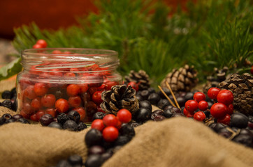 Black Rowan and red Rowan, pine cones and branches on the background of burlap. Preparations for the winter. Gift of nature.