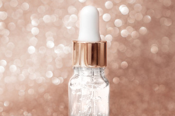 Anti aging serum with collagen and peptides in glass bottle with dropper on golden background....