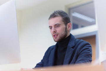 Fototapeta premium Young male Businessman working on modern computer. Businessman using innovative technologies. Businessman working on computer, software developing with modern tech on virtual screen.