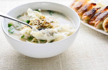 Wonton soup with spring onion served in a white bowl, selective focus
