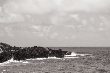 black and white of waves hitting rocks