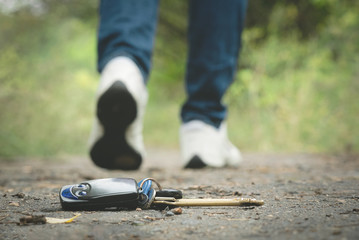 Lost keys on a road in park and walking away female legs in a shoes.