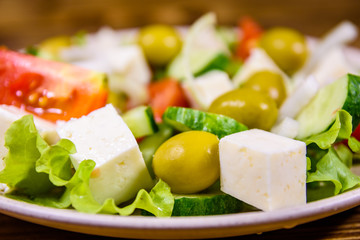 Ceramic plate with greek salad on wooden table