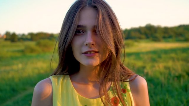 young beautiful girl with long hair walks in a summer field on sunset, girl model. Walk in nature and fresh air