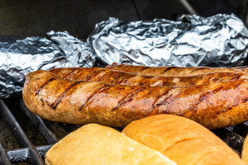 Mild Italian sauasge, buns and baked potatoes on the grill. Calgary, Alberta, Canada