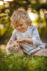 Little curly boy with a redhead cat, outdoor