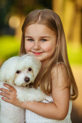 Little girl with a maltese puppy, outdoor summer