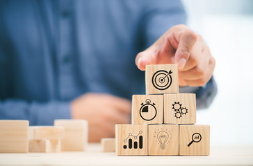 businessman hand stack woods block step on table. business development concept.arranging wood block with icon business strategy and Action plan.