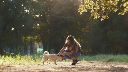 Attractive young woman playing with jack russel terrier in park during beautiful sunset, super slow motion