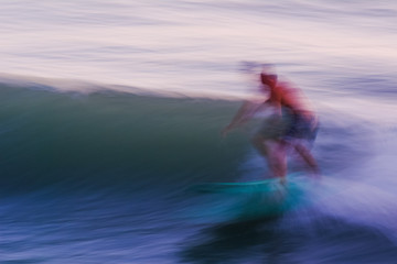 Panned shot of a surfer catching a wave, unrecognizable person