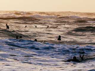 Unknown surfers take the last wave at sunset