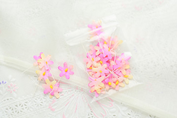 Fototapeta na wymiar Handmade paper flowers on white fabric background, pink and yellow, decor for invitation card.