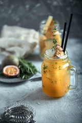 Tropical cocktail with passion fruit, lime and mint on a gray background. Real concept, cocktail workspace. Food concept, food style, Copy space, food advertising for magazines and social networks.